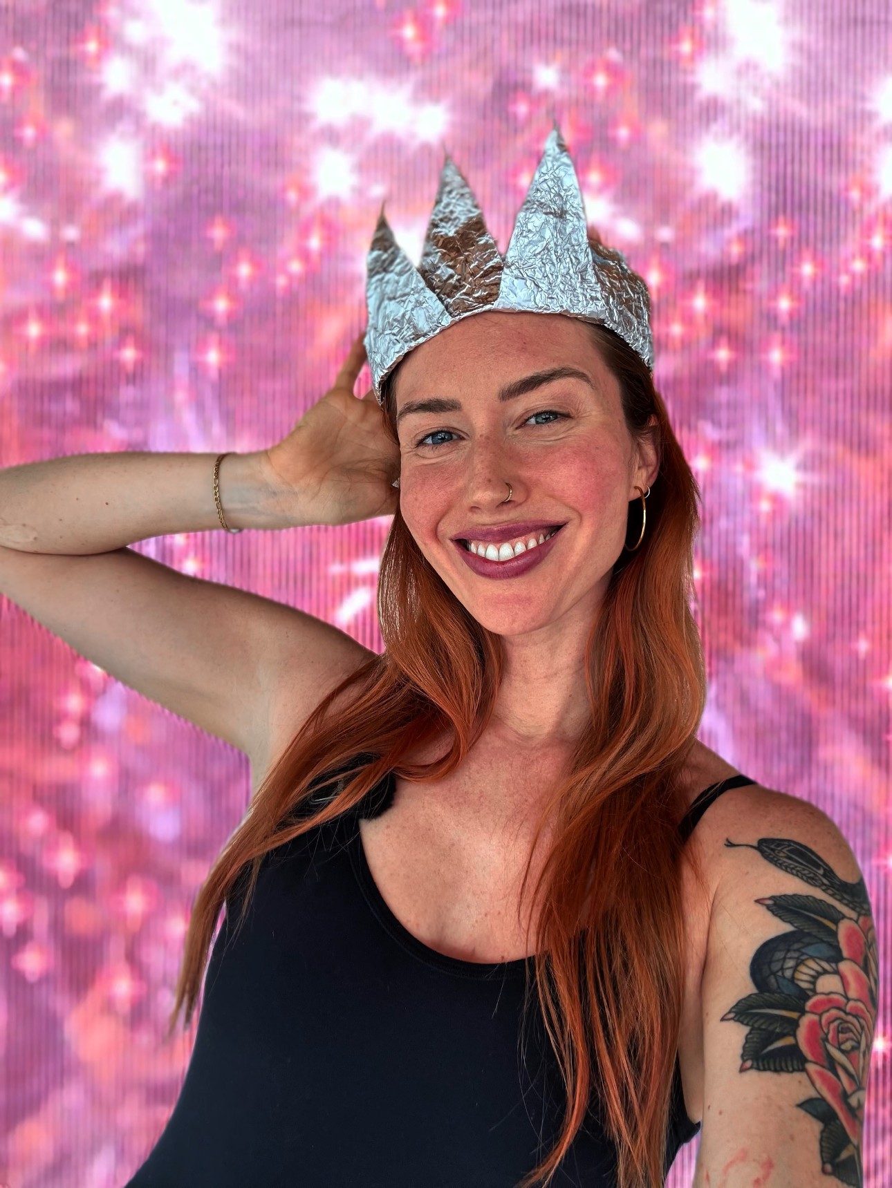 Bre Lee wearing a silver foil crown on a pink sparkle backdrop