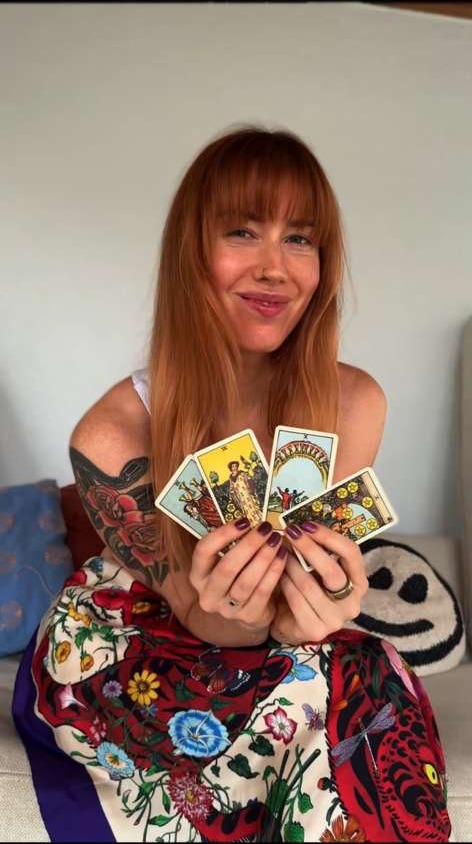 Bre Lee holding a fan of tarot cards on the couch